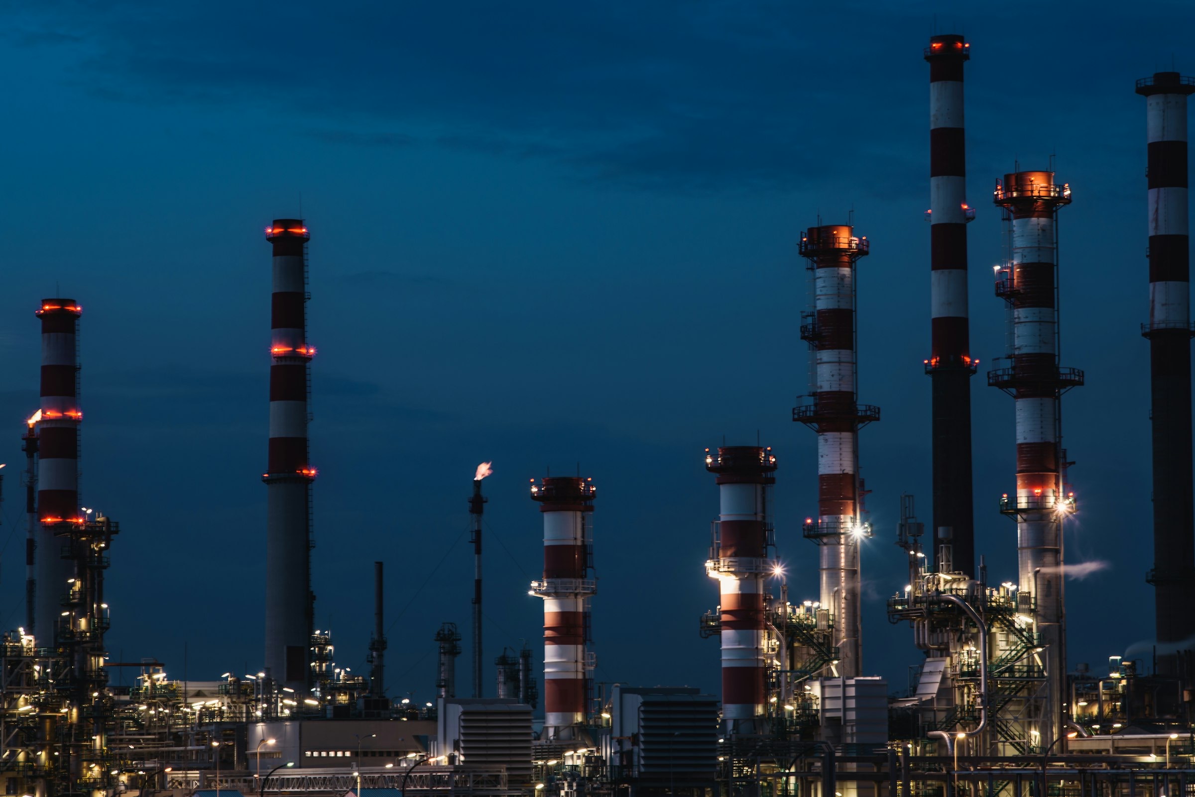 Chemical plant smokestacks illuminated against twilight sky